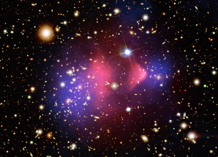 A composite image of the various observations of the galaxy cluster 1E
0657-66.  The galaxies making up the cluster are from optical images
taken by the Hubble Space Telescope and Magellen.  On either side of
the center of the cluster, the pink clumps show the hot gas detected
by Chandra. Just outside this gas (shown in blue) are regions where
the bulk of the matter resides. This matter, detected via
gravitational lensing, shows that dark matter makes up most of the
mass of the cluster.