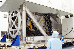 Inside Hangar AE at Cape Canaveral Air Force Station (CCAFS), workers observe the canister being lifted from the Swift spacecraft, which is enclosed in a protective cover.